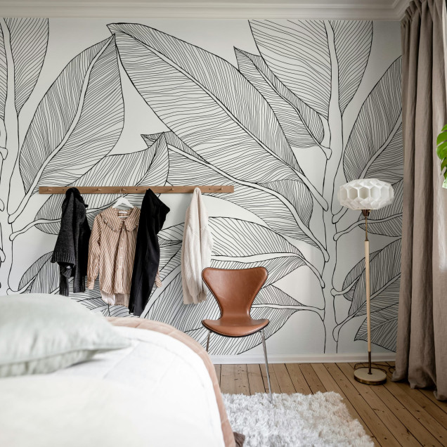 Fototapet cu design de frunze stilizate în linii negre pe un fundal alb, într-un living modern.