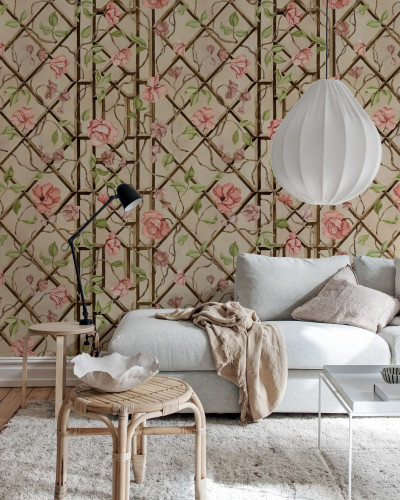 Fototapet cu flori roz și frunze verzi pe un fundal bej cu o rețea de sârmă stilizată, într-un living decorat modern.