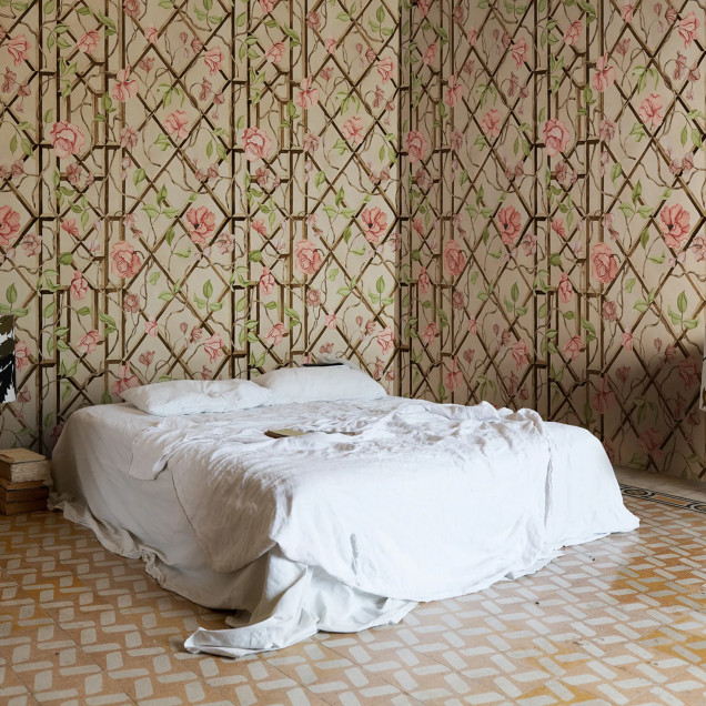 Fototapet cu flori roz și frunze verzi pe un fundal bej cu o rețea de sârmă stilizată, într-un living decorat modern.