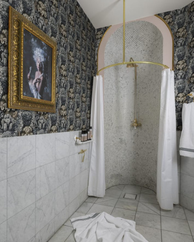 Tapet cu model floral, cu fundal negru și design floral auriu și teal, într-o baie cu o cabină de duș cu pereți din marmură