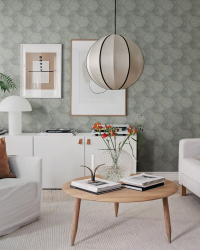 Tapet geometric Hexagon Tiles in nuanța Jade, cu model hexagonal modern, aplicat pe un perete din living, alături de un canapea alba si un fotoliu alb.