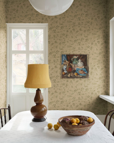 Tapet Mila Olive Green cu model de frunze delicate, într-un dining luminos, cu masă albă și accente lemnoase.