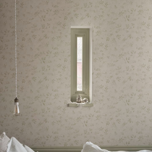 Tapet Mila Light Green cu model delicat de frunze verzi pe un perete lângă o fereastră și un dulap alb.