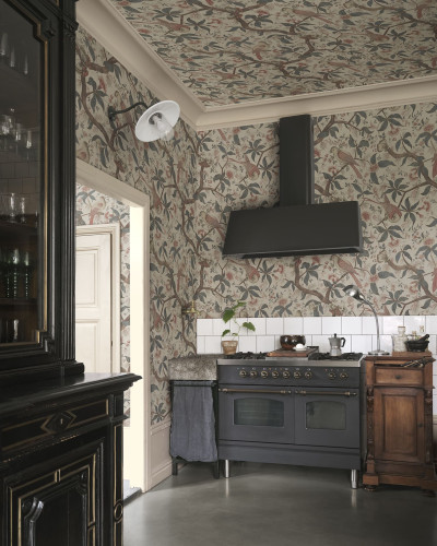 Tapet Alexa, Misty Blue cu model de păsări și ramuri florale, aplicat pe pereții și tavanul unei bucătării amenajate în stil clasic-vintage cu mobilier închis la culoare și aragaz negru.