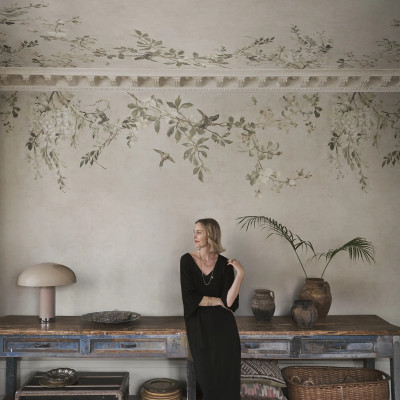 Fototapet Luca Sand cu model floral delicat, ramuri cu flori albe și păsări pe un fundal nisipiu, într-o amenajare interioară elegantă și relaxantă.