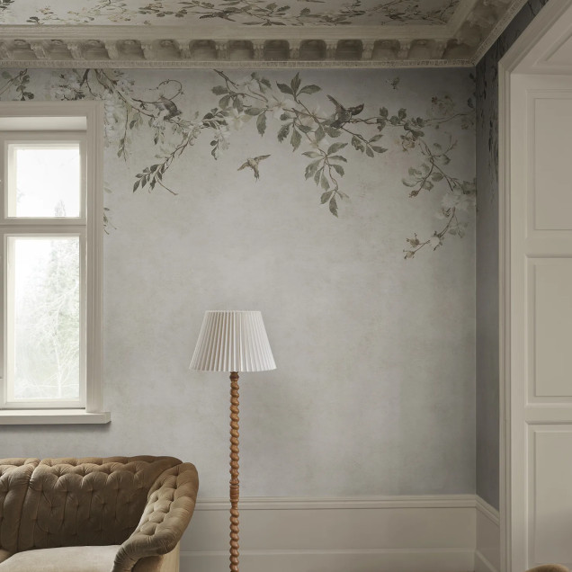 Fototapet Luca Sand cu model floral delicat, ramuri cu flori albe și păsări pe un fundal nisipiu, într-o amenajare interioară elegantă și relaxantă.