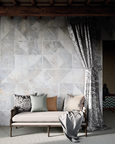 Tapet modern cu model geometric Tintagel, Grey, ilustrat pe un perete din living, lângă un fotoliu gri cu perne decorative.