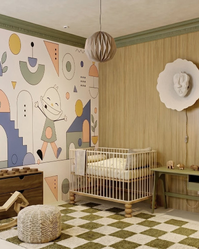Fototapet cu design geometric si un personaj vesel, ilustrat in pasteluri, pe peretele unei camere de copii, langa un patut si o comoda.