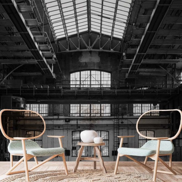 Tapet Industrial Grey, cu un design modern, inspirat de spațiile industriale. Acesta prezintă o imagine a unui hală cu o structură metalică și ferestre mari, în nuanțe de gri.