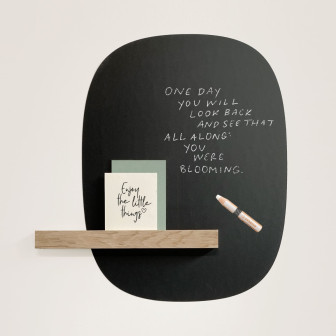 Tablă magnetică neagră cu mesaj scris și etajeră din lemn