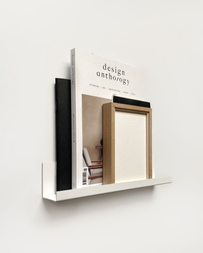 Poliță metalică simplă pentru perete, albă, cu un design minimalist. Pe ea sunt așezate un cadru, o carte și o figurină.