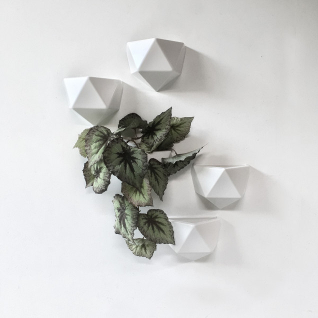 Ghiveci din plastic alb, cu design geometric, atașat pe un perete alb, conținând un carnet galben și markere galbene.