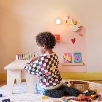 Copil desenând pe o tablă magnetică autoadezivă în formă de casă, roz deschis