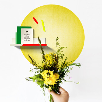 Sticker magnetic galben pe un perete alb, cu un raft și un buchet de flori galbene