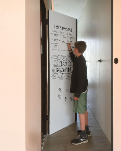 Băiat scriind pe o tablă magnetică albă