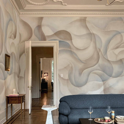 Tapet lavabil cu design abstract în nuanțe de albastru și bej. Se poate observa o canapea gri și o masă de cafea din lemn în fața tapetului.