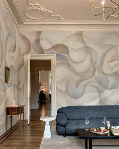 Tapet lavabil cu design abstract în nuanțe de albastru și bej. Se poate observa o canapea gri și o masă de cafea din lemn în fața tapetului.