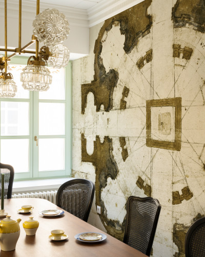 Tapet cu design clasic inspirat de arhitectura florentină,  aflat pe un perete în living, alături de o masă de dining, scaune și un candelabru cu cristale.