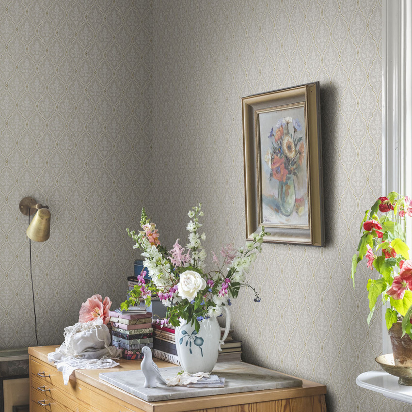 Tapet cu design clasic Lillie Sandstone, cu motive delicate in nuante de gri si auriu, perfect pentru a crea o atmosfera eleganta si primitoare.