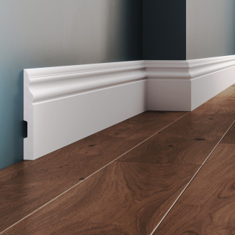 Plintă decorativă din polimer rigid, albă, montată la baza peretelui.